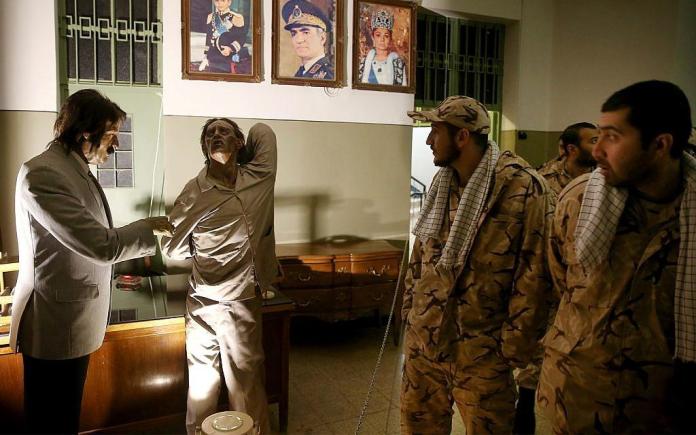Vojnici Iranske revolucionarne garde gledaju izložbu u bivšem zatvoru koji je vodila predrevolucionarna obavještajna služba SAVAK, a sada muzej, gdje su izložene voštane lutke ispitivača i zatvorenika koji se muči, u Teheranu, Iran. Portreti šaha, kraljice Farah i njegovog sina, prijestolonasljednika Reze Pahlavija, koji sada živi u egzilu u SAD-u, vise iznad scene, 7. siječnja 2019. (AP Photo/Ebrahim Noroozi)