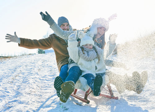 Семья катается на санках по снегу